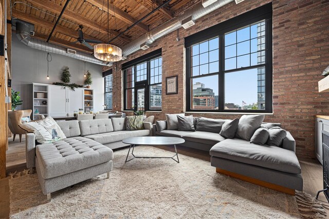 living room with brick wall, beamed ceiling, wooden ceiling, hardwood / wood-style floors, and a towering ceiling