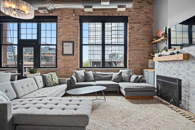 living room featuring a high ceiling, a chandelier, and brick wall