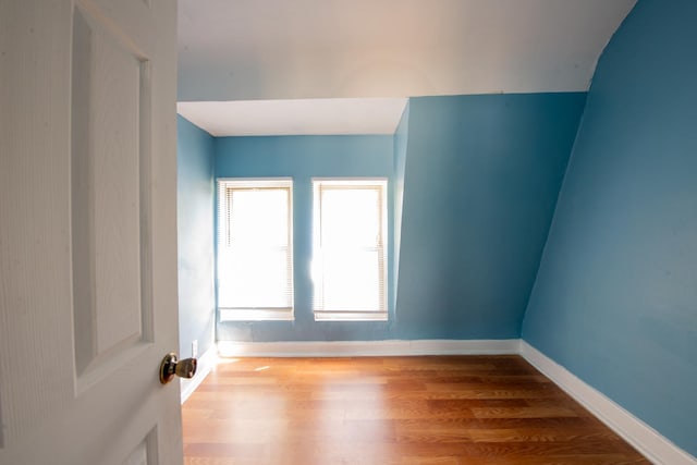 spare room with baseboards and wood finished floors