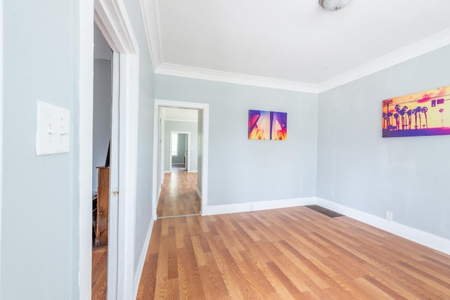 unfurnished room with baseboards, ornamental molding, and wood finished floors