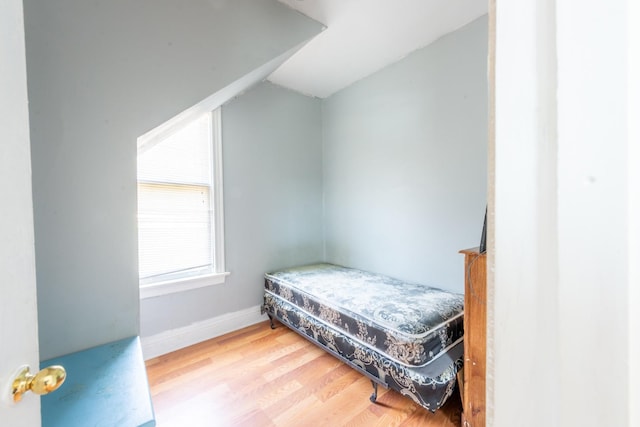 bedroom with vaulted ceiling, baseboards, and wood finished floors