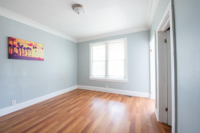 unfurnished room featuring baseboards, crown molding, visible vents, and wood finished floors