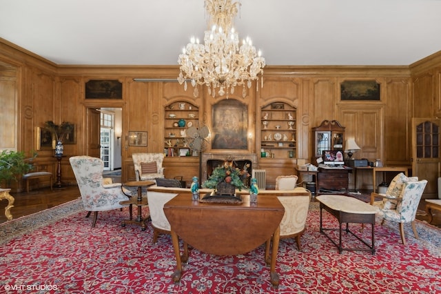 living room with built in features, wood walls, a chandelier, and crown molding