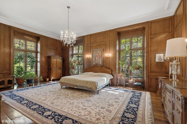 bedroom with a notable chandelier, a decorative wall, crown molding, dark wood-type flooring, and wood walls