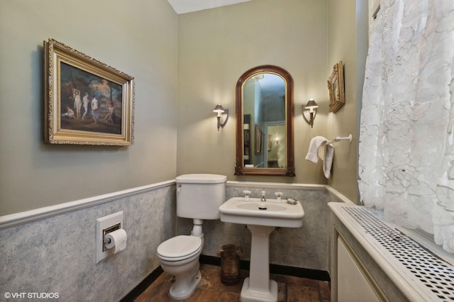 full bath featuring toilet and wainscoting