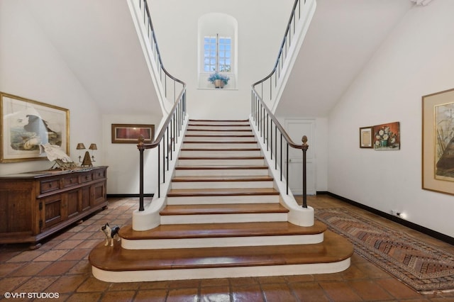 stairs featuring high vaulted ceiling and baseboards