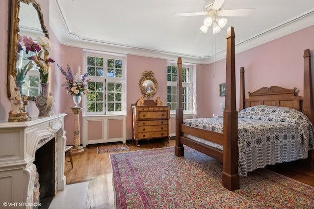 bedroom featuring crown molding, multiple windows, wood-type flooring, and ceiling fan