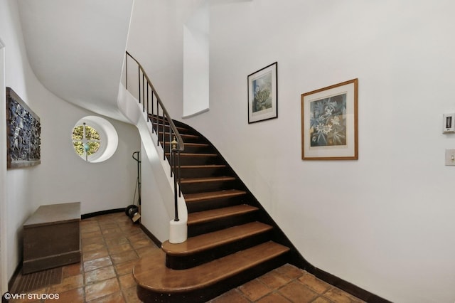 stairs with baseboards and stone tile floors