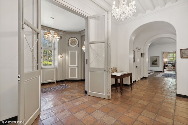 foyer entrance featuring a wealth of natural light, crown molding, and a chandelier