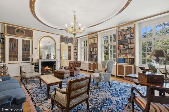 living room featuring a tray ceiling, wood-type flooring, and an inviting chandelier