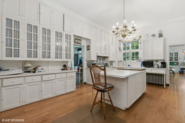 kitchen with light hardwood / wood-style flooring, a kitchen island, a chandelier, and white cabinets