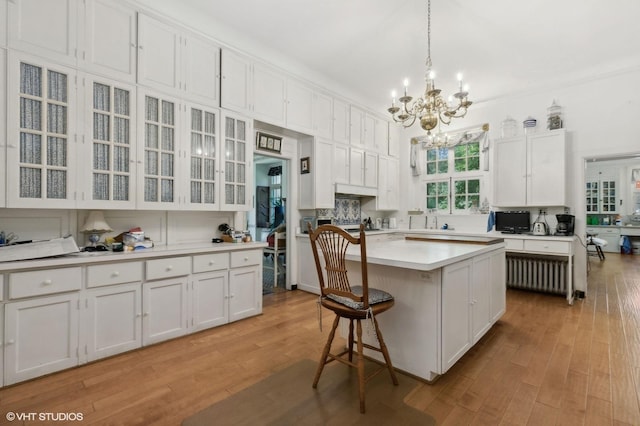 kitchen featuring a chandelier, white cabinetry, light countertops, a kitchen island, and radiator