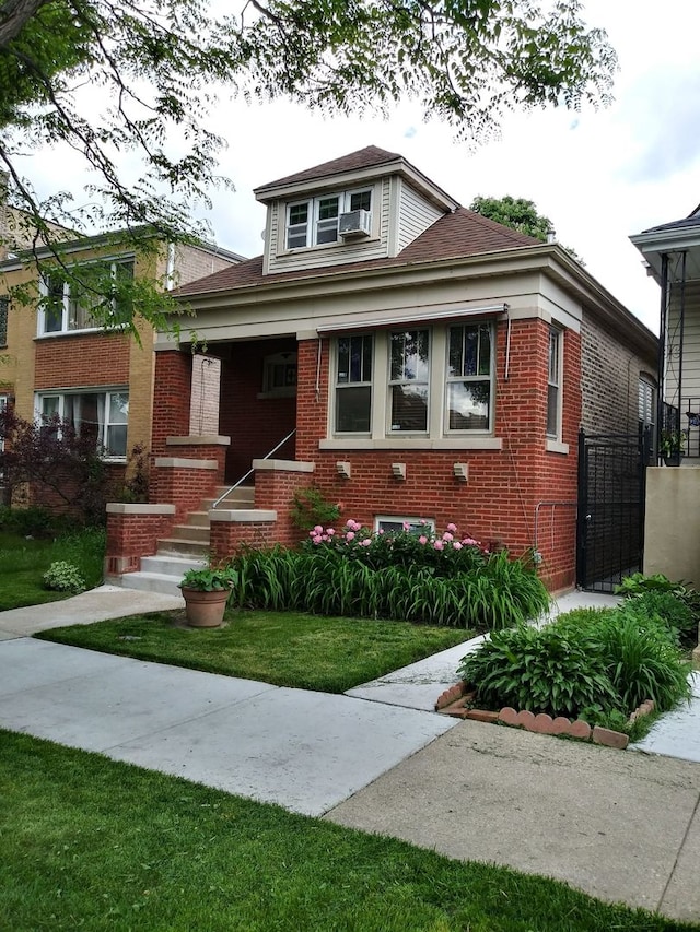 bungalow with brick siding and a front yard