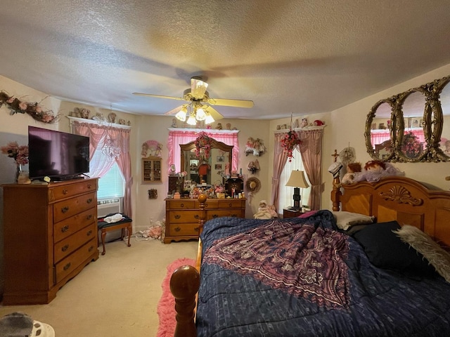 bedroom with ceiling fan, light colored carpet, and a textured ceiling