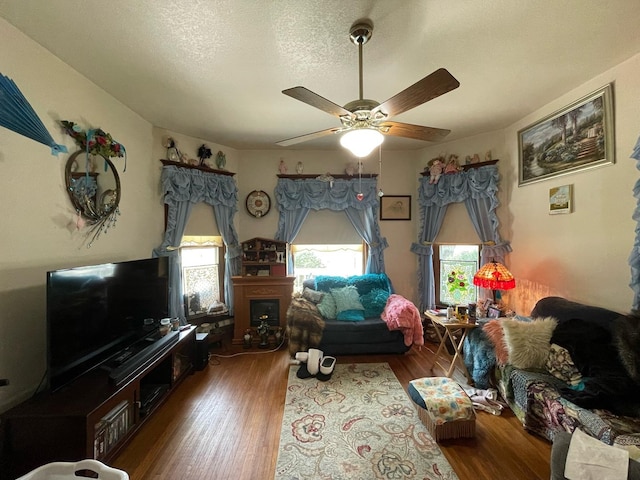 living room featuring hardwood / wood-style flooring, ceiling fan, and a textured ceiling