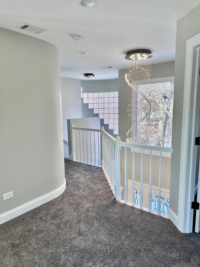 corridor with a notable chandelier, carpet flooring, and plenty of natural light