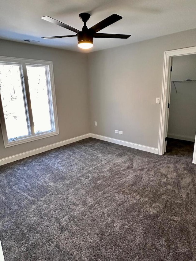 unfurnished bedroom featuring a walk in closet, carpet flooring, a closet, and ceiling fan