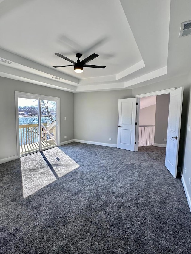 carpeted empty room featuring ceiling fan and a raised ceiling