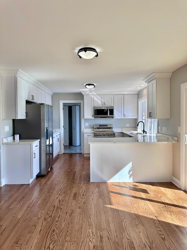 kitchen with white cabinets, sink, stainless steel appliances, and hardwood / wood-style flooring