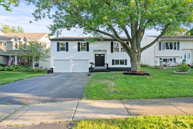 bi-level home featuring aphalt driveway, a garage, cooling unit, and a front yard