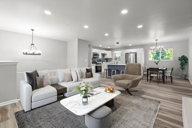 living area with a notable chandelier, recessed lighting, light wood-type flooring, and baseboards