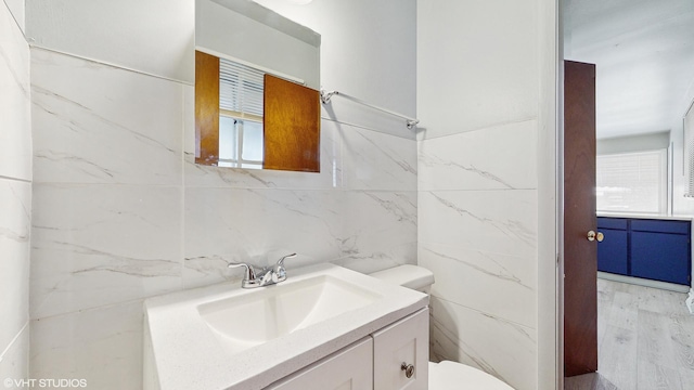 bathroom with vanity, wood-type flooring, tile walls, and a wealth of natural light