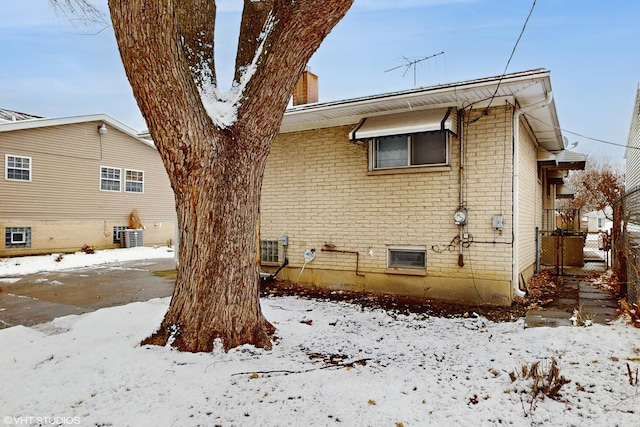 snow covered rear of property with cooling unit