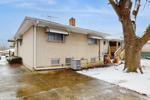 snow covered rear of property with central air condition unit