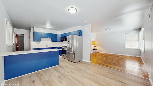 kitchen with sink, light hardwood / wood-style flooring, stainless steel appliances, and blue cabinets