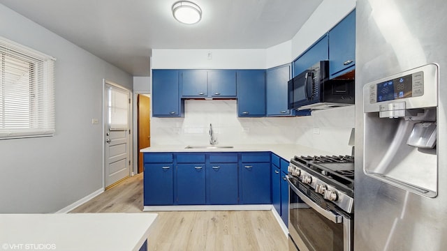 kitchen with blue cabinetry, sink, light hardwood / wood-style floors, and appliances with stainless steel finishes