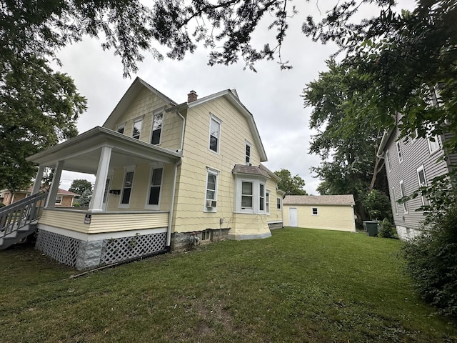 back of property with a porch, a chimney, and a lawn