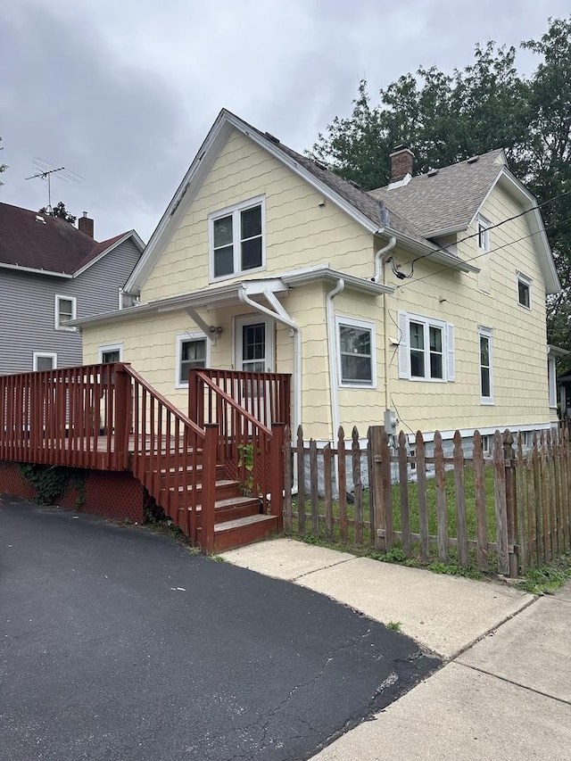 back of house featuring a deck, a chimney, and a fenced front yard