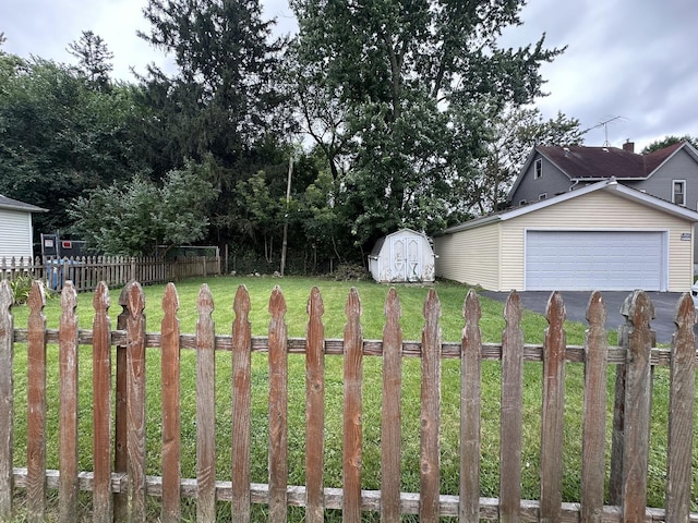 view of yard with a shed, aphalt driveway, fence, and an outdoor structure
