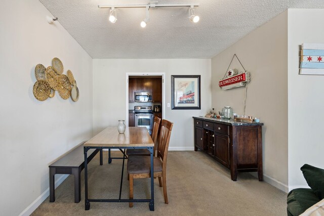 dining room featuring track lighting, a textured ceiling, and light colored carpet