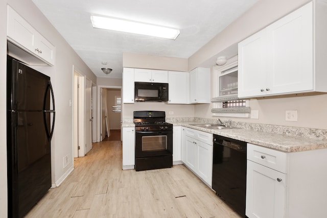 kitchen with black appliances, light hardwood / wood-style flooring, sink, and white cabinets