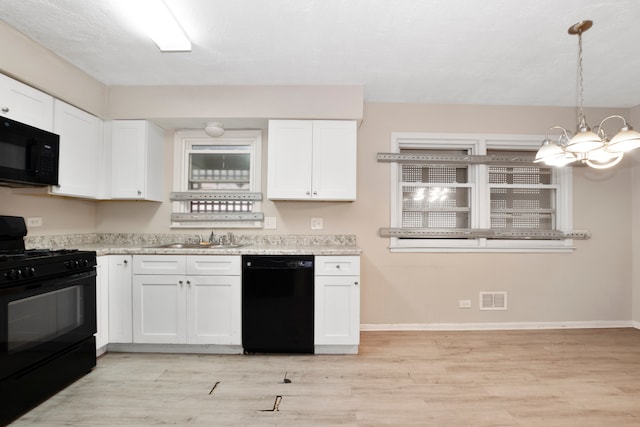 kitchen with an inviting chandelier, decorative light fixtures, black appliances, sink, and light wood-type flooring