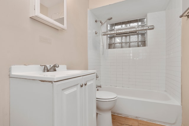 full bathroom with wood-type flooring, toilet, tiled shower / bath, and vanity