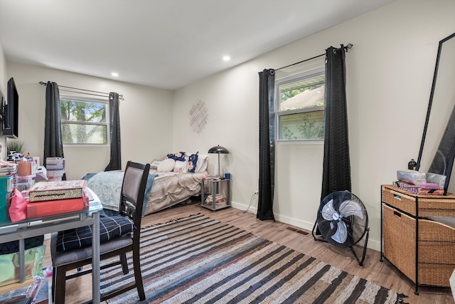 bedroom with multiple windows and light wood-type flooring