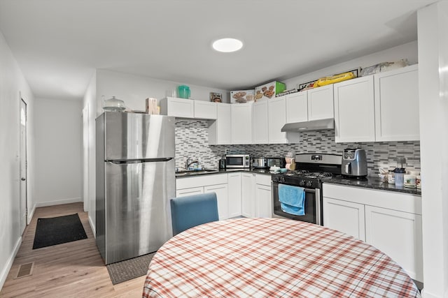 kitchen with stainless steel appliances, sink, backsplash, light wood-type flooring, and white cabinetry