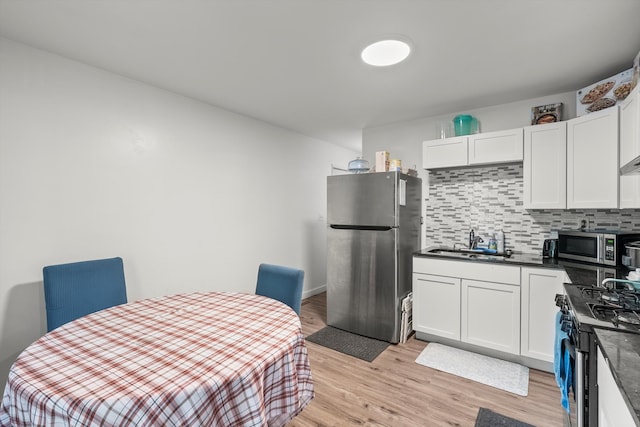 kitchen featuring white cabinets, stainless steel appliances, light hardwood / wood-style flooring, and tasteful backsplash