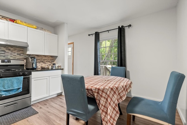 kitchen with decorative backsplash, stainless steel range oven, light wood-type flooring, and wall chimney range hood