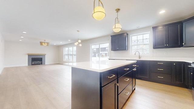 kitchen with decorative light fixtures, a kitchen island, light wood-type flooring, and sink