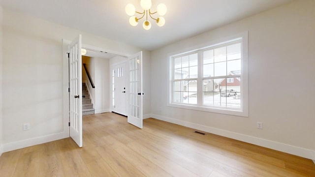 unfurnished room featuring light wood-type flooring and a notable chandelier