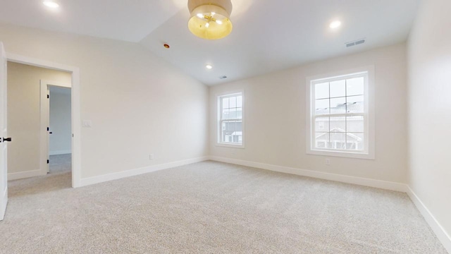 unfurnished room with light colored carpet and vaulted ceiling