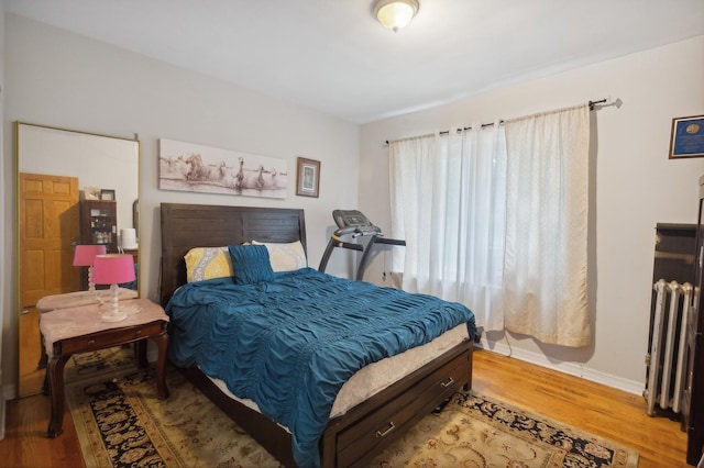 bedroom featuring baseboards, radiator, and wood finished floors