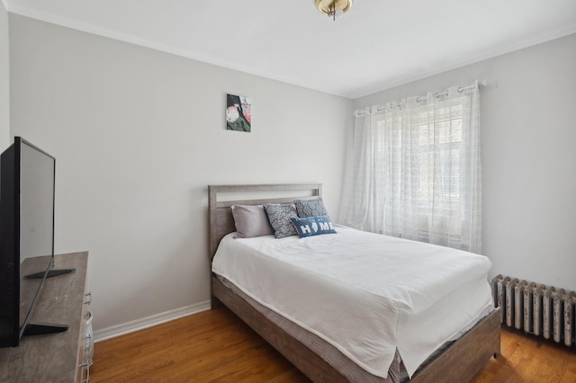 bedroom featuring radiator, wood finished floors, and baseboards