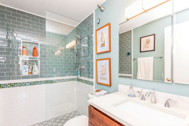 bathroom featuring vanity, a tile shower, and toilet