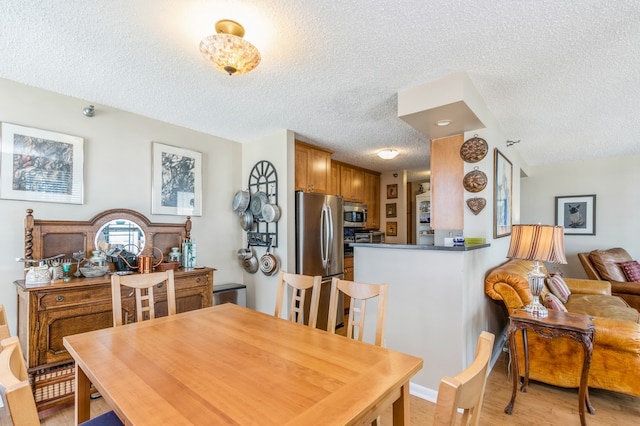 dining area with light hardwood / wood-style flooring and a textured ceiling