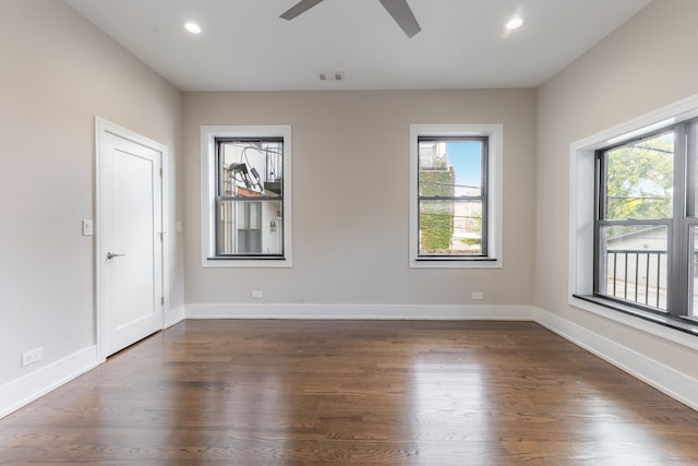 spare room featuring dark hardwood / wood-style floors, ceiling fan, and a wealth of natural light