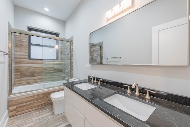 full bathroom with tile patterned flooring, combined bath / shower with glass door, toilet, and dual bowl vanity